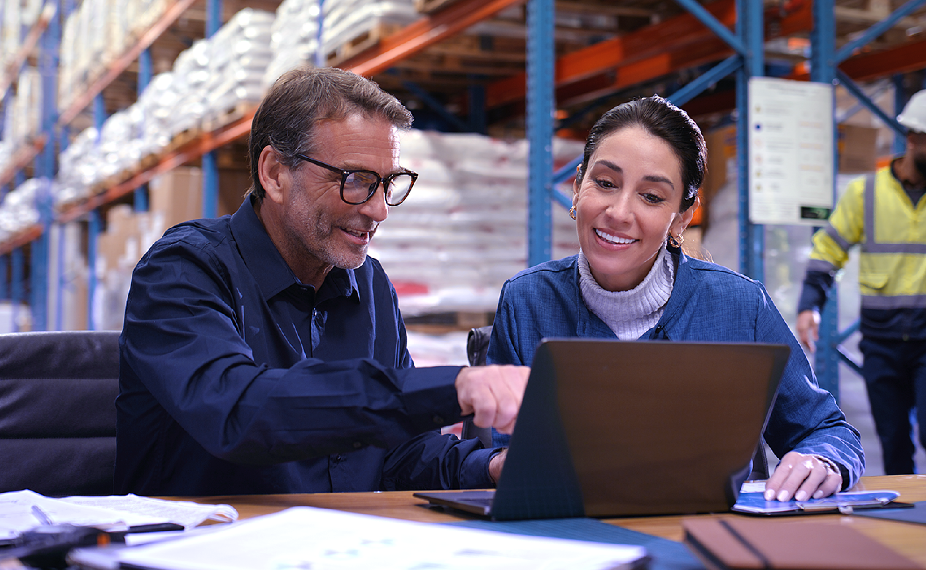 Two employees in warehouse using computer